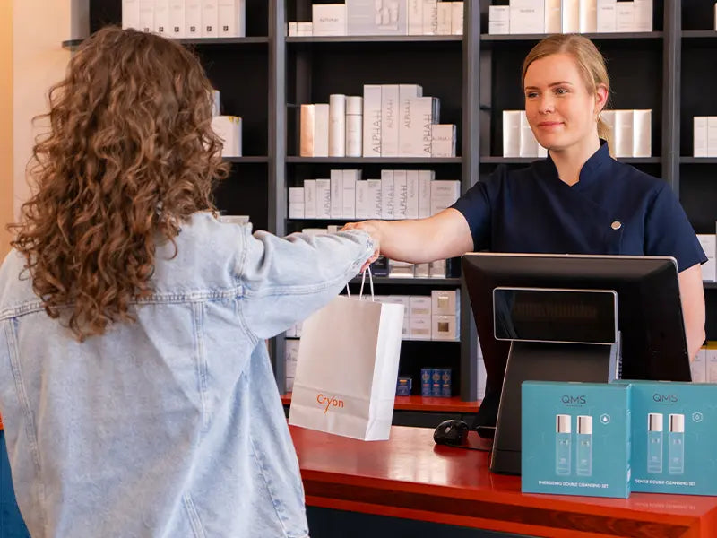 Cryon medewerker overhandigt een tasje met schoonheidsproducten aan een klant in de schoonheidssalon in Breda.